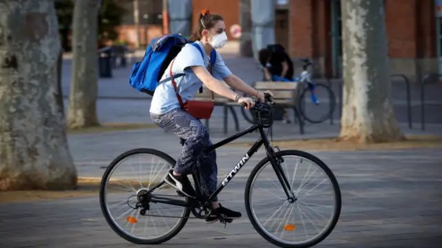 Young woman in mask riding bike in Toulouse, France