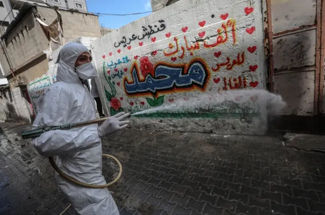 A worker sprays disinfectant on a street in Gaza City (19 March 2020)