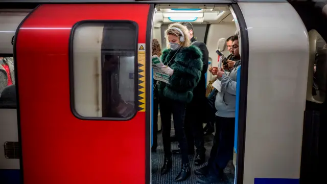 A commuter wears a mask as a precaution while travelling on a London Underground