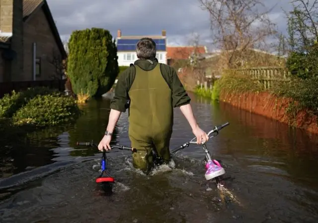 Man walking bikes through flood water