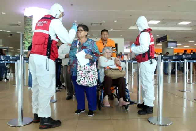 Health workers check passengers arriving at Mariscal Sucre International Airport regarding the spread of the COVID-19 virus worldwide