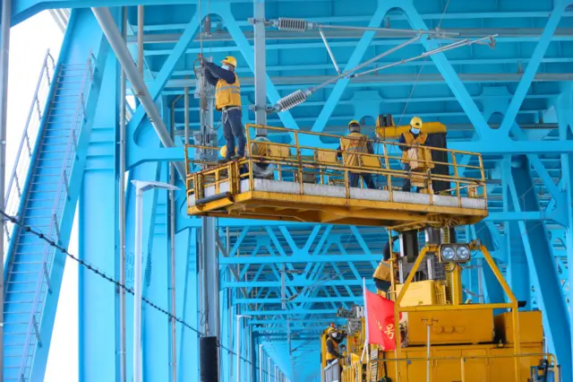 Workers lay the power lines for trains on Hutong Yangtze Bridge under construction across the Yangtze River in Nantong in east China's Jiangsu province, China.