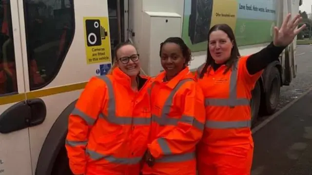 Workers pose by bin lorry