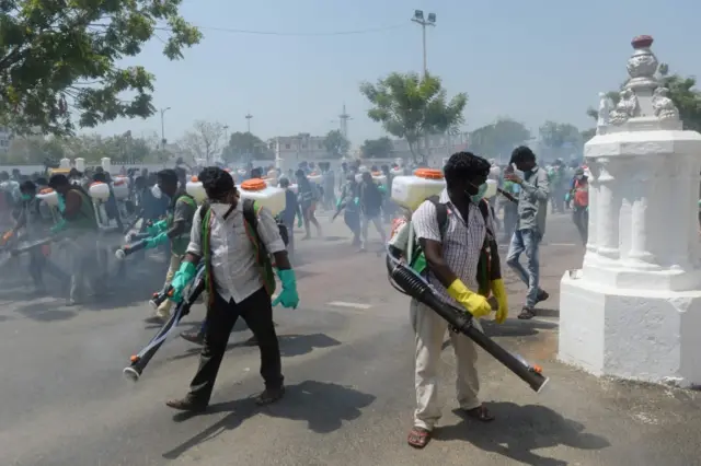 Health workers wearing facemasks amid concerns over the spread of the COVID-19 novel coronavirus, spray disinfectant at the corporation office in Chennai on March 20, 2020. (