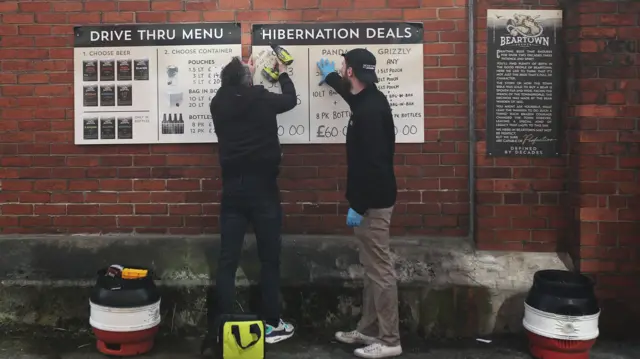 Workers put up beer menus at the Beartown Brewery drive thru in Congleton as the spread of the coronavirus disease (COVID-19) continues