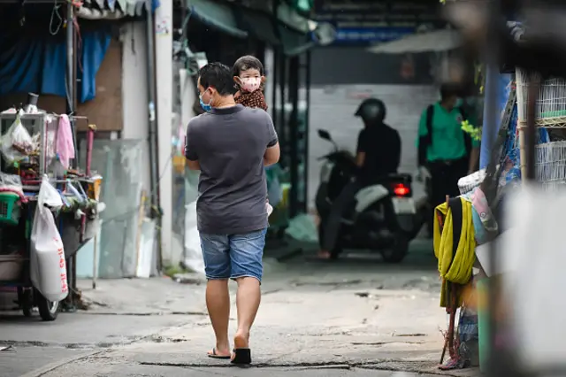 A man carrying a kid while wearing protective masks