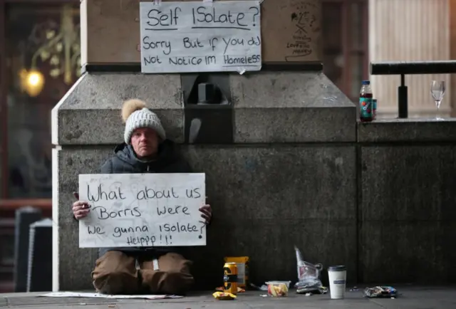 A homeless man holds up a sign outside Westminster underground station as the spread of the coronavirus disease (COVID-19) continues, in London