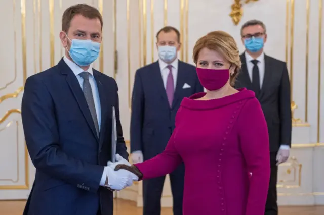 Prime Minister Igor Matovic and President Zuzana Caputova wearing protective face masks shake hands as they attend the cabinet"s inauguration at Presidential Palace in Bratislava