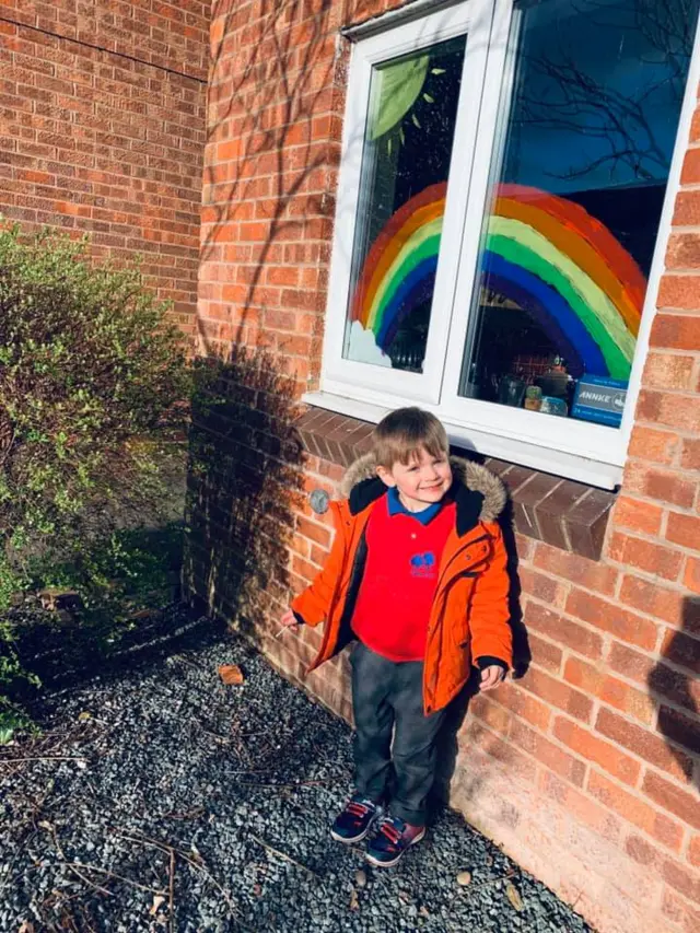 Son stood outside with rainbow artwork