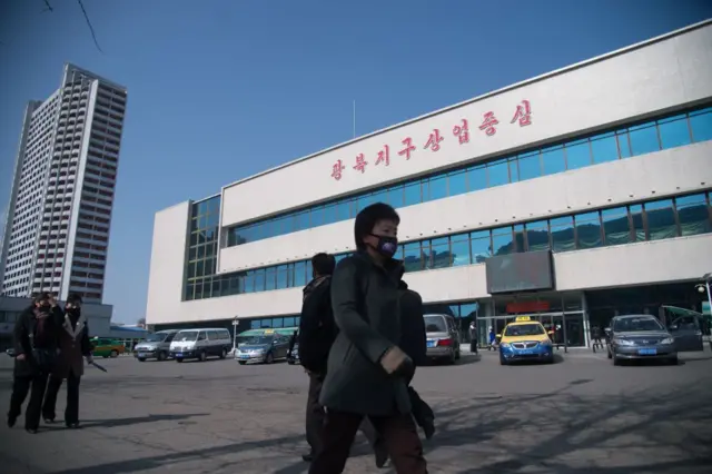 People wearing face masks walk down Kwangbok street in Pyongyang on February 26, 2020.