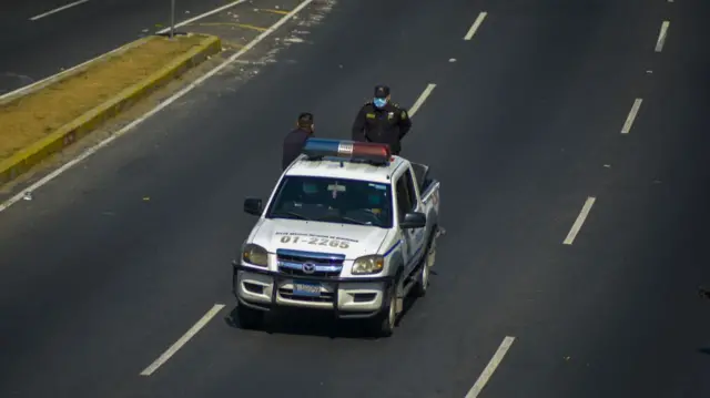 Police patrol the empty streets in El Salvador's capital during the coronavirus pandemic, 23 March 2020