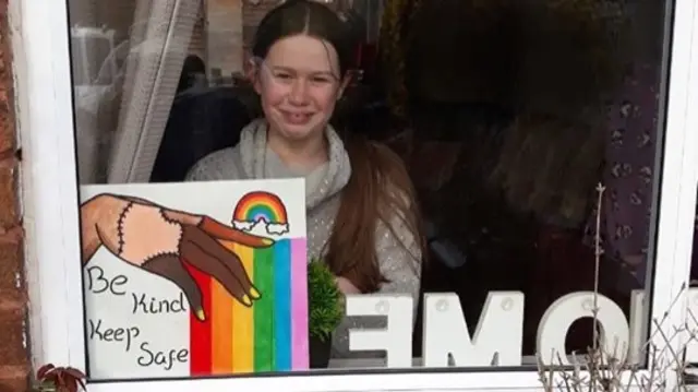 Pic of daughter in the window with rainbow artwork