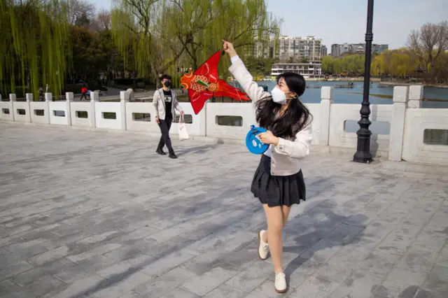 A girl wearing a mask flies a kite at Taoranting Park on March 21, 2020