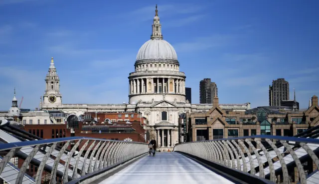 A person walks across Millennium Bridge in London