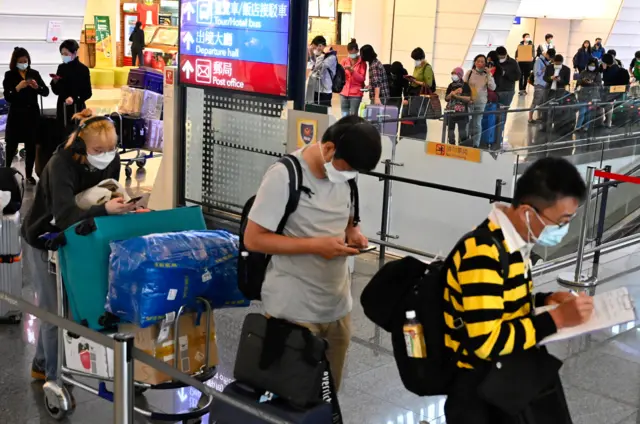 Passengers line up for government assigned taxies after arriving at Taoyuan Airport on March 19, 2020