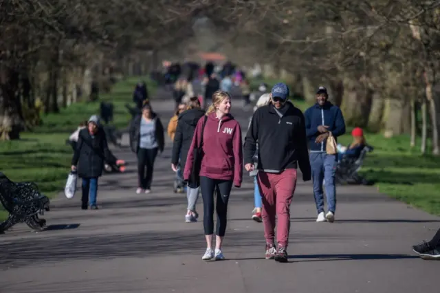 People are seen walking in Greenwich park on 22 March