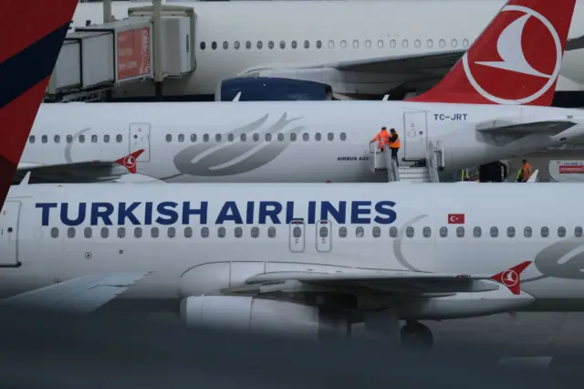 Ground staff are seen on an aircraft operated by Turkish Airlines.