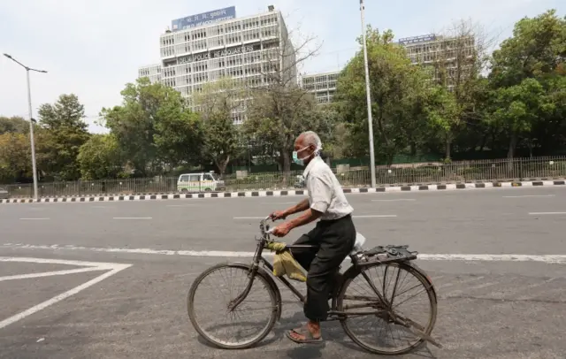 An Indian man rides a bicycle on a deserted street