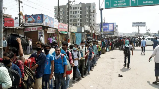 Passengers queue to board buses in Patna, 23 March 2020