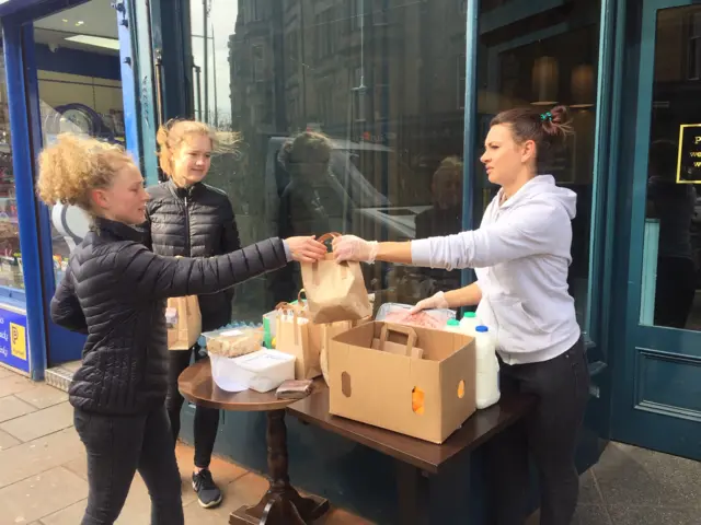 Kasia Smolarek, manager of Project Coffee, hands Rachel Pearson and Mairi Murchison