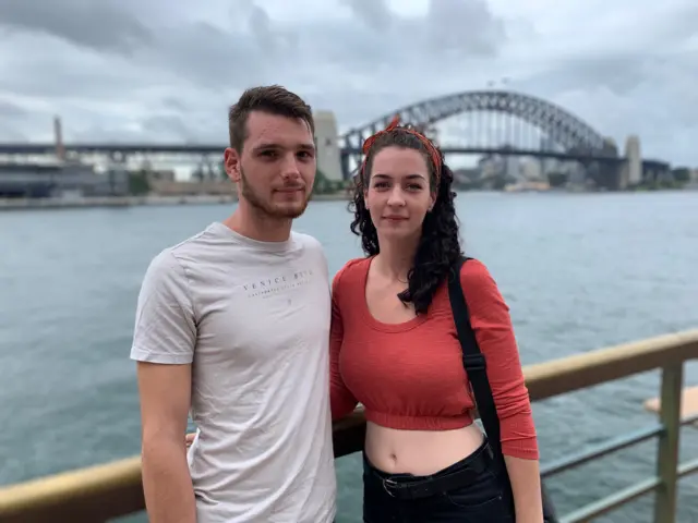 Backpackers Harry and Ash stand in front of the Sydney Opera House