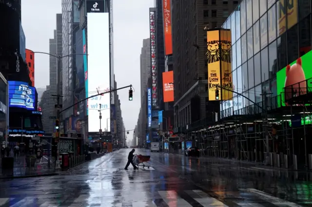 A homeless person pushes his belongings through a deserted Times Square following the outbreak of coronavirus disease in the Manhattan borough of New York City, U.S., March 23, 2020.