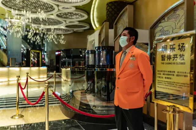 An employee wearing a protective mask stands at the entrance of a gambling hall