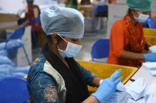 Employees wearing facemasks amid concerns of the spread of the COVID-19 coronavirus work at the production line of facemasks at Salus Products, a manufacturer of surgical disposable products, on the outskirts of Ahmedabad on March 12, 2020.