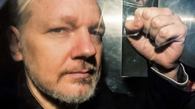 Julian Assange gesturing with his fist from a prison van in May 2019