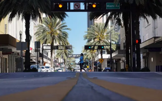 A pedestrian crosses a street void of much traffic as large numbers of people stay home in an effort to contain the coronavirus pandemic on March 24, 2020 in Miami, Florida