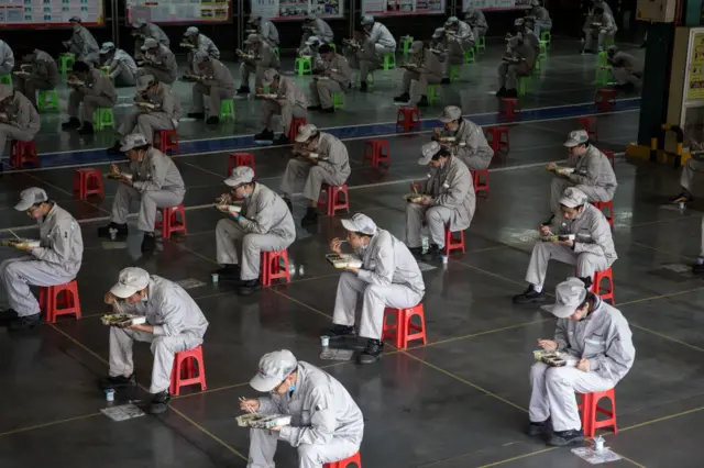 Employees eat their lunch while staying 2 meters away from each other at the Dongfeng Fengshen plant