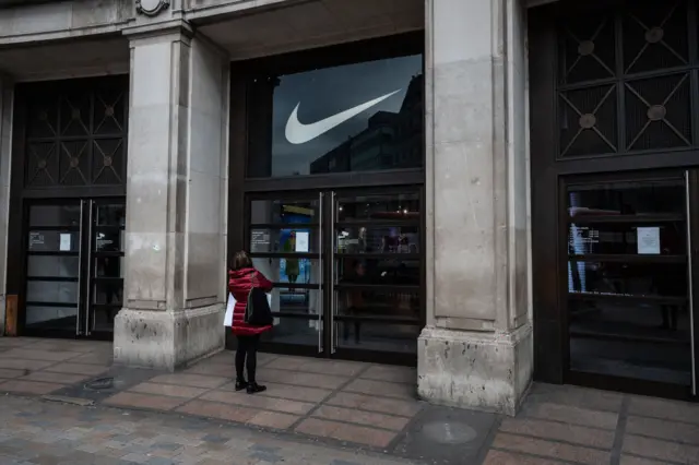 A woman reads the sign on the door of the closed Niketown store on Oxford Street, London.