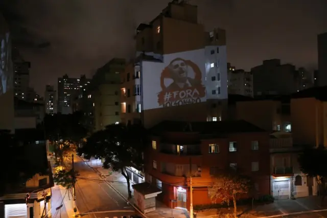 An image depicting Brazil"s President Jair Bolsonaro and the phrase "out Bolsonaro" is projected during Bolsonaro's statement on TV about the coronavirus disease (COVID-19) outbreak in Sao Paulo