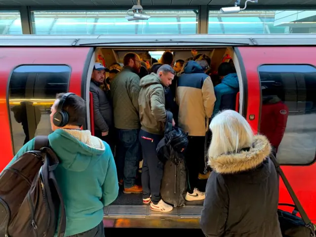 assengers squeeze on to a busy Central Line underground train at Stratford station, east London, March 23