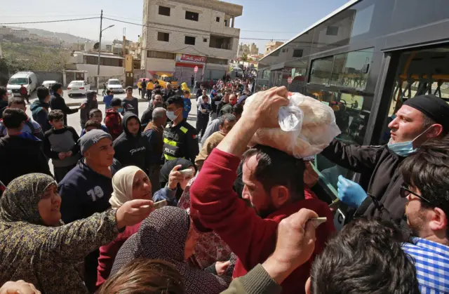 People queue to buy bread from a municipal bus in Marka, a suburb of Amman, Jordan (24 March 2020)