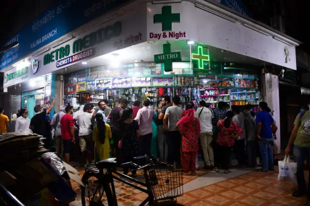 People gather at a pharmacy to buy supplies