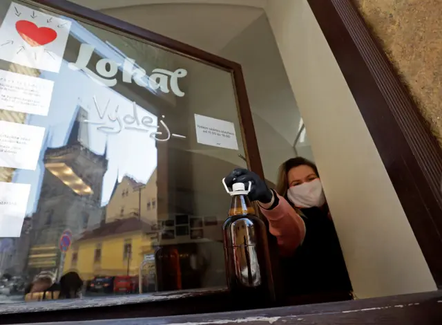 A waitress hands a plastic cup of beer through a window