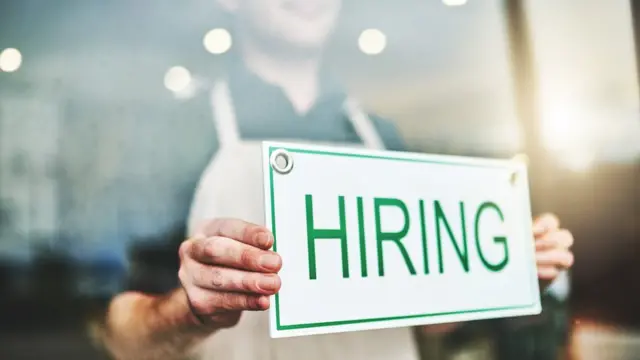 Man puts hiring sign in a window