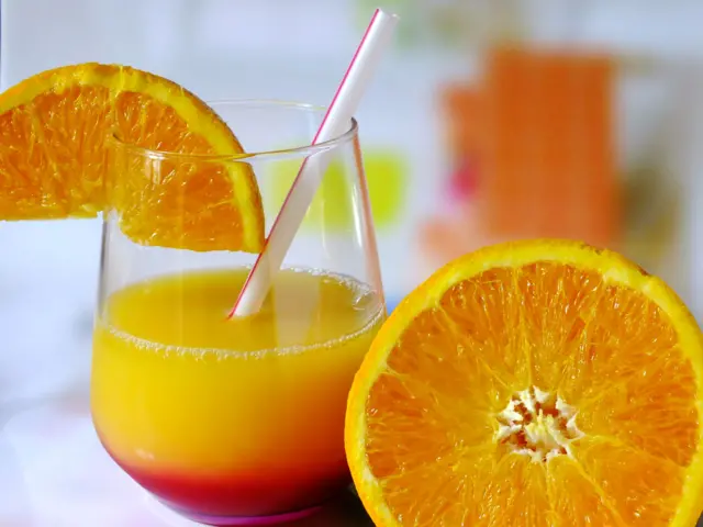 A glass of orange juice with a halved orange.