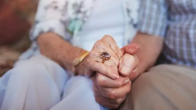 Elderly people holding hands