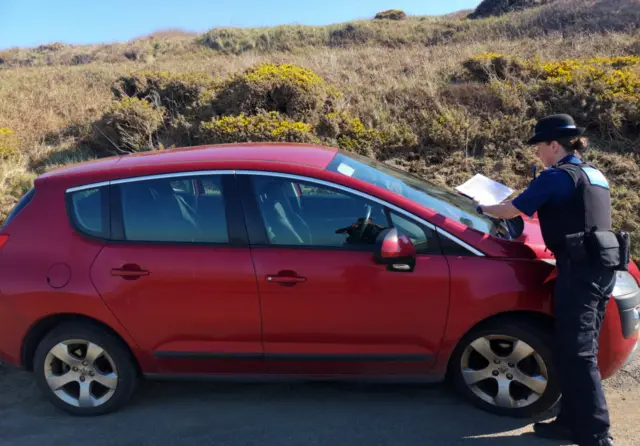 Police officer fixes notice to a car in Pembrokeshire