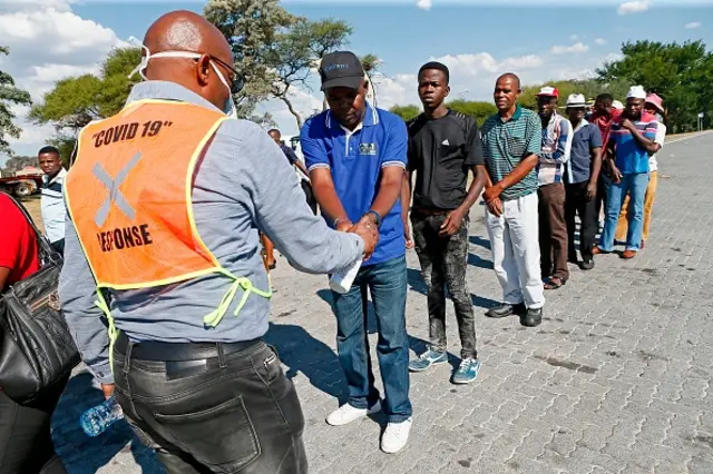 A Limpopo provincial health official uses a disinfectant spray on travelers