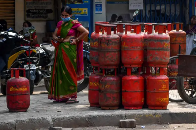 Woman checking her phone by a pile of gas cylinders in Mumbai