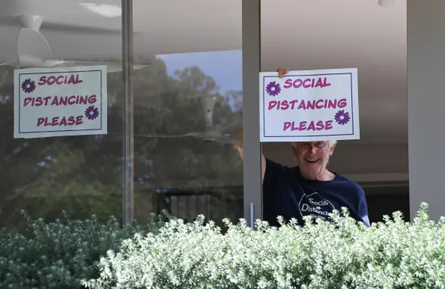 A man holds a sign form his home in Sydney