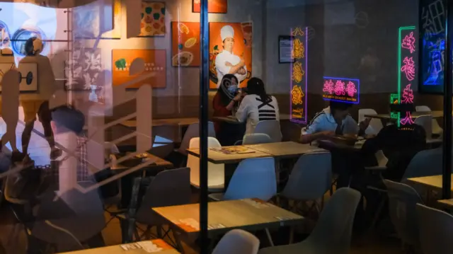 Customers sit in a quiet restaurant in Hong Kong, 26 March 2020