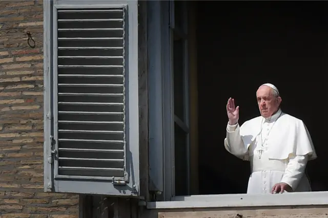 Pope Francis salutes from the window of the apostolic palace overlooking an empty St Peter's square