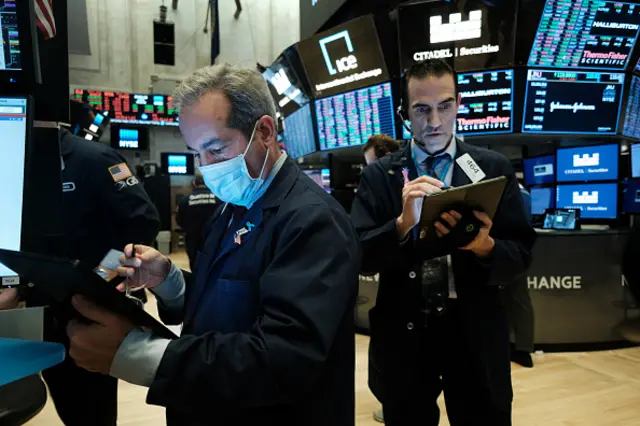 Traders, some in medical masks, work on the floor of the New York Stock Exchange