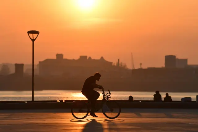 A cyclist passes by as the sun sets on Liverpool Pier Head in Liverpool, north-west England on March 26, 2020