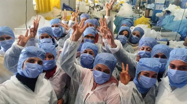 Factory workers give peace sign