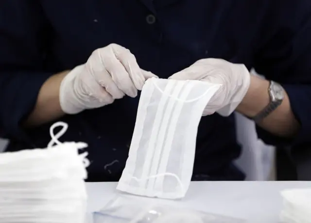 Workers wearing face masks make production of face masks